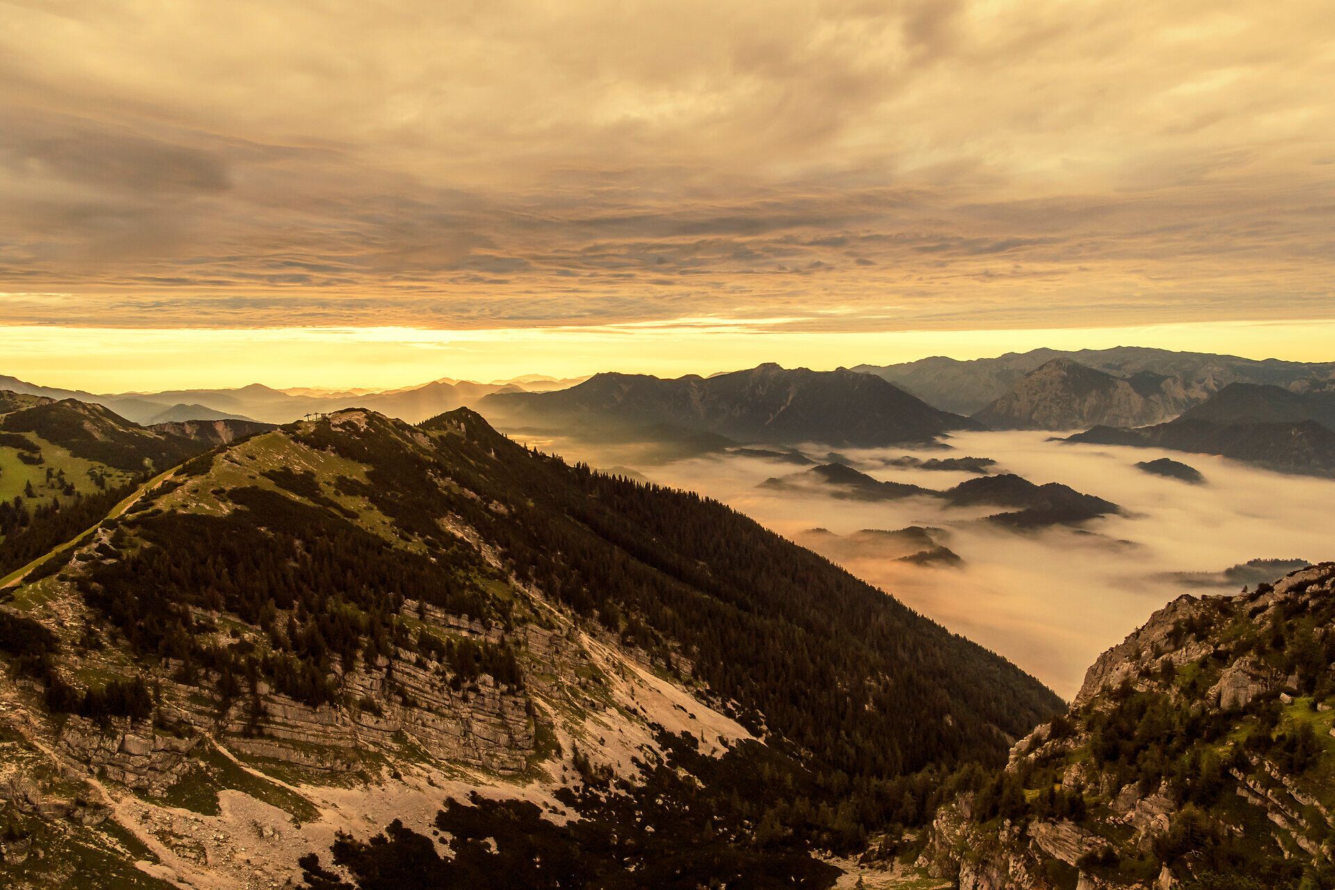 Die majestätischen Berge erheben sich stolz in den Himmel, während sanfte Nebelschwaden die Täler umhüllen. Ein goldener Sonnenuntergang taucht die Landschaft in warmes Licht und lädt zu unvergesslichen Erlebnissen in der Natur ein.