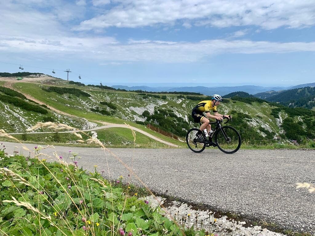 Ein Rennradfahrer bei der Auffahrt auf der Hochkar-Bergstraße, im Hintergrund ist die Hochkarbahn zu sehen.