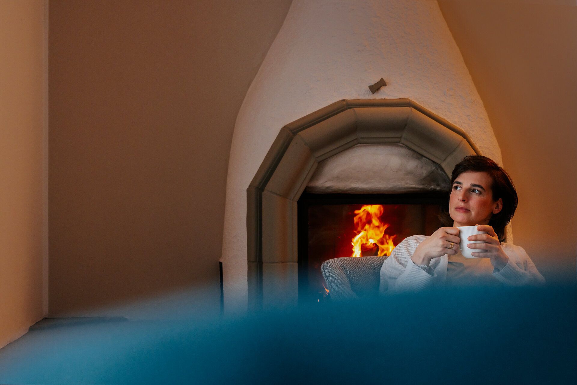 In der gemütlichen Atmosphäre der Ötscher Lodge genießt eine Familie die wohlige Wärme des Kamins, während draußen der Winter seine weiße Pracht entfaltet. Eine Tasse heißer Schokolade in der Hand, blicken sie verträumt in die Flammen und lassen den Alltag hinter sich.