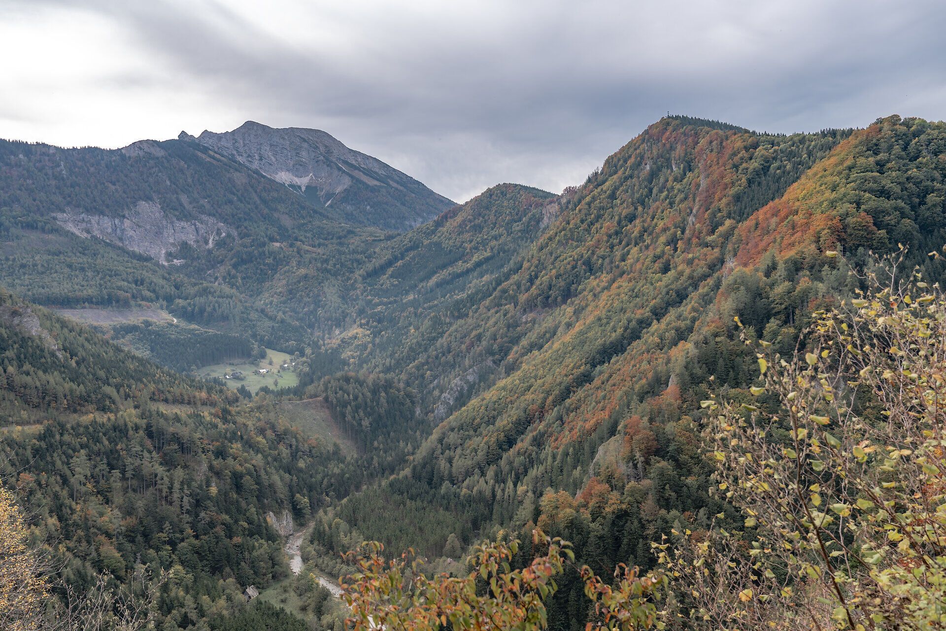Die sanften Hügel und majestätischen Berge umarmen das Tal, während die bunten Blätter des Herbstes in warmen Tönen leuchten. Ein klarer Himmel und die frische Bergluft laden Wanderer ein, die unberührte Natur zu erkunden und die Ruhe dieser malerischen Landschaft zu genießen.