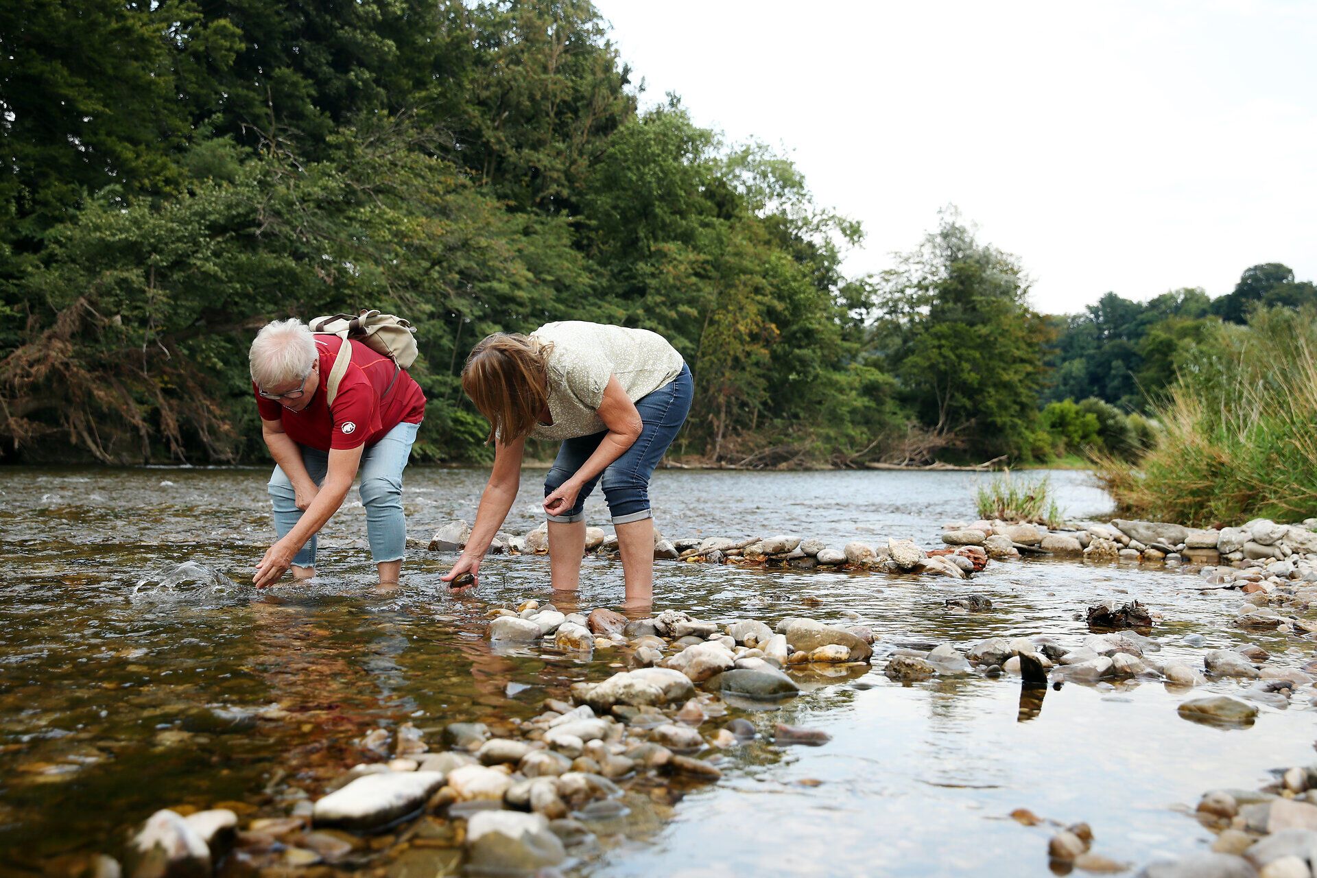 Zwei Frauen stehen in einem Fluss im Naturpark Ybbstal im Mostviertel und suchen nach Steinen.