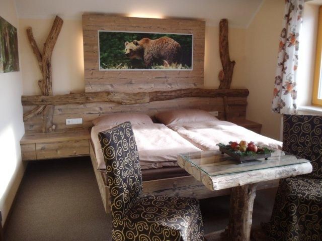 Rustikales Schlafzimmer mit Holzmöbeln und Bärenbild an der Wand.