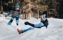 In der winterlichen Landschaft toben ein fröhlicher Junge und sein Vater im frischen Schnee. Die strahlende Sonne und die schneebedeckten Bäume schaffen eine zauberhafte Atmosphäre, die zum Spielen und Entdecken einlädt. Hier wird der Winter in den Ybbstaler Alpen zum unvergesslichen Erlebnis für die ganze Familie.