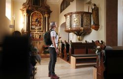 Pilgerin in Kirche bei barockem Altar.