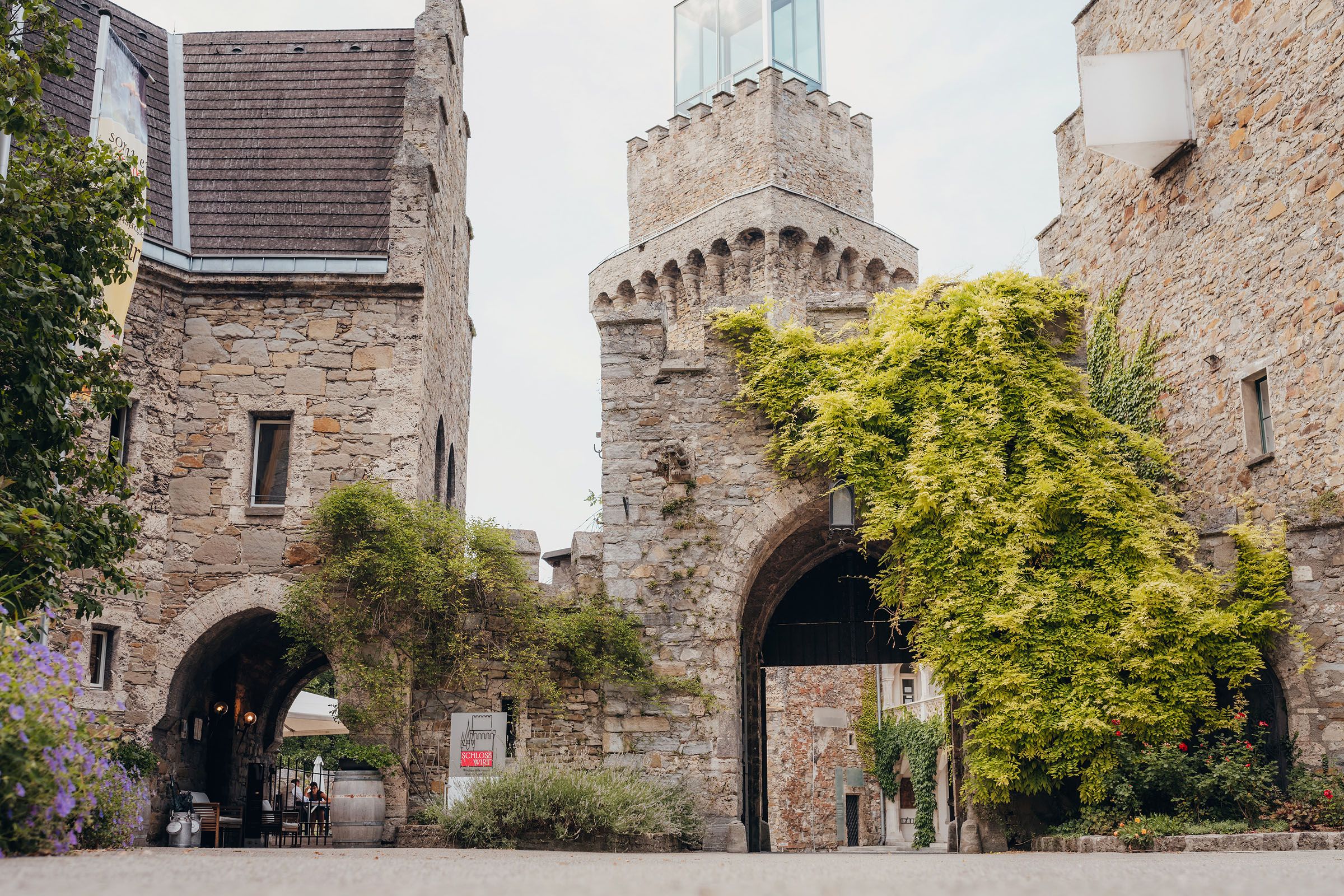 Eingangstor von Schloss Rothschild mit bewachsenen Steinmauern.