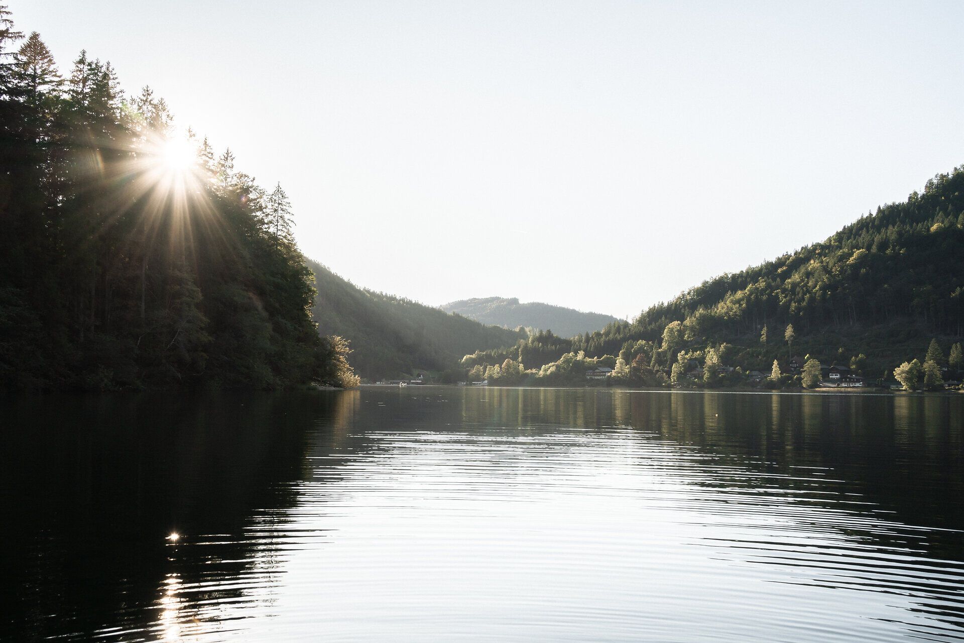 Sonnenlicht fällt über den Lunzer See am Ybbstalradweg im Mostviertel, umgeben von bewaldeten Bergen.