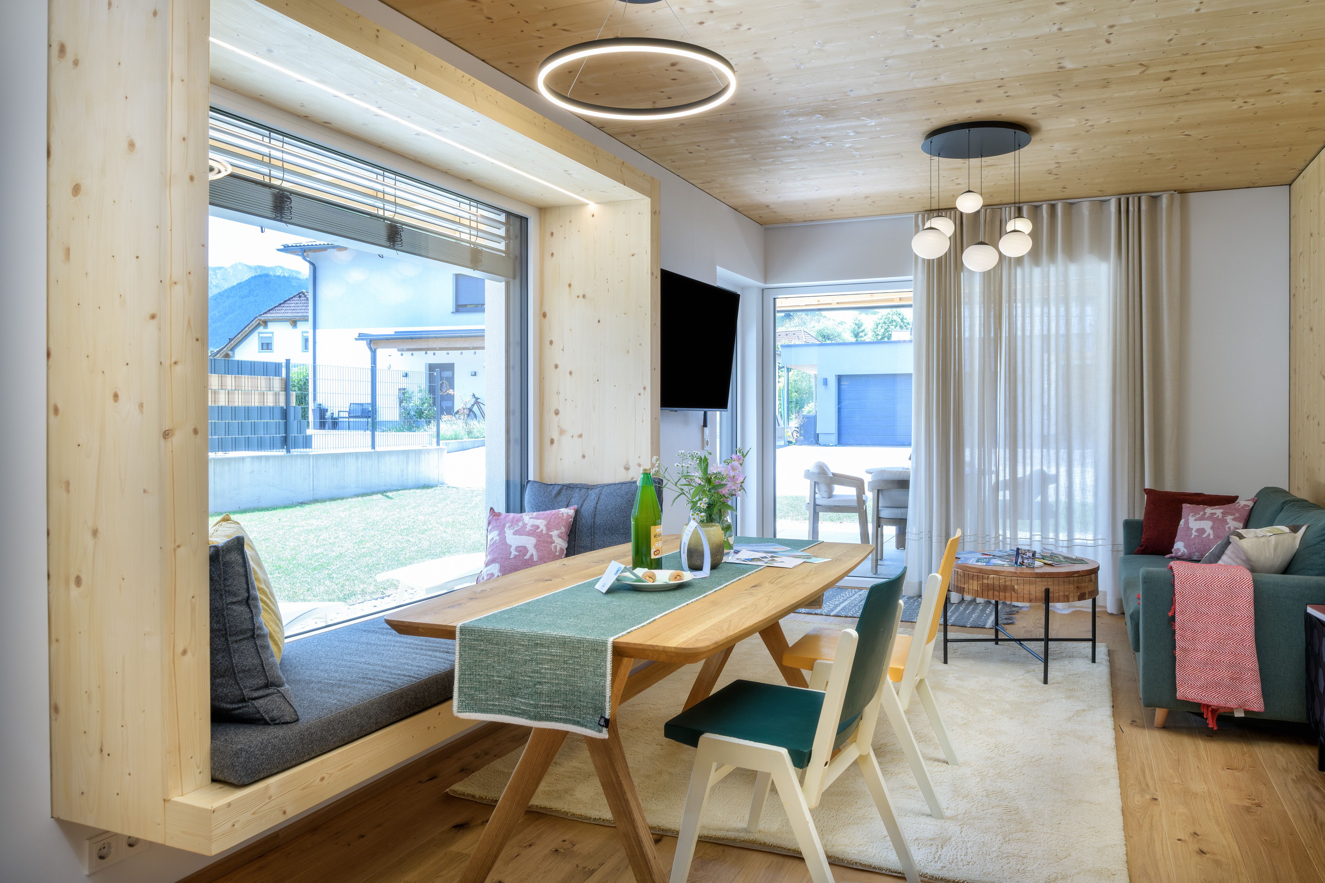 Modernes Wohnzimmer mit Holzelementen, großem Fenster und stilvoller Einrichtung.