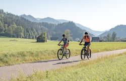 Zwei Radfahrer gleiten entspannt durch die malerische Landschaft der Ybbstaler Alpen, umgeben von saftigem Grün und majestätischen Bergen. Die klare Luft und die strahlende Sonne schaffen eine einladende Atmosphäre für Abenteuerlustige und Naturliebhaber. Hier wird das Radfahren zum Genuss und die Schönheit der Natur zum Erlebnis.