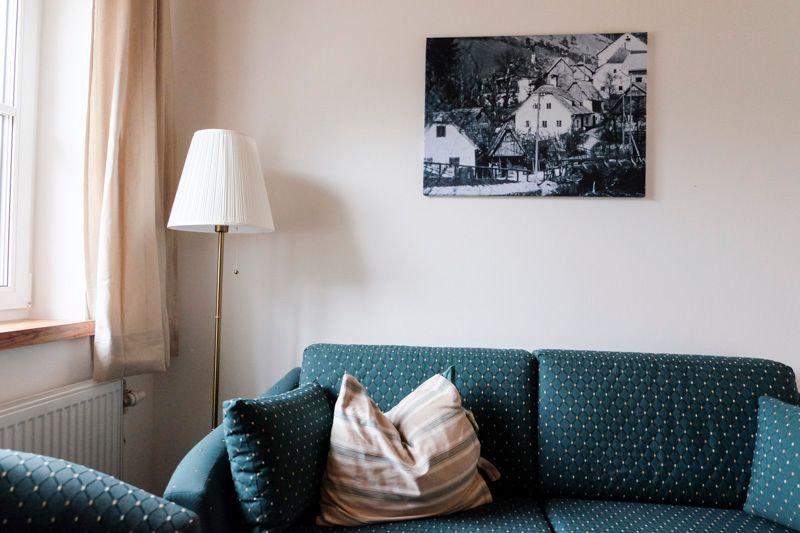 Wohnzimmer mit Sofa, Stehlampe und Bild an der Wand.
