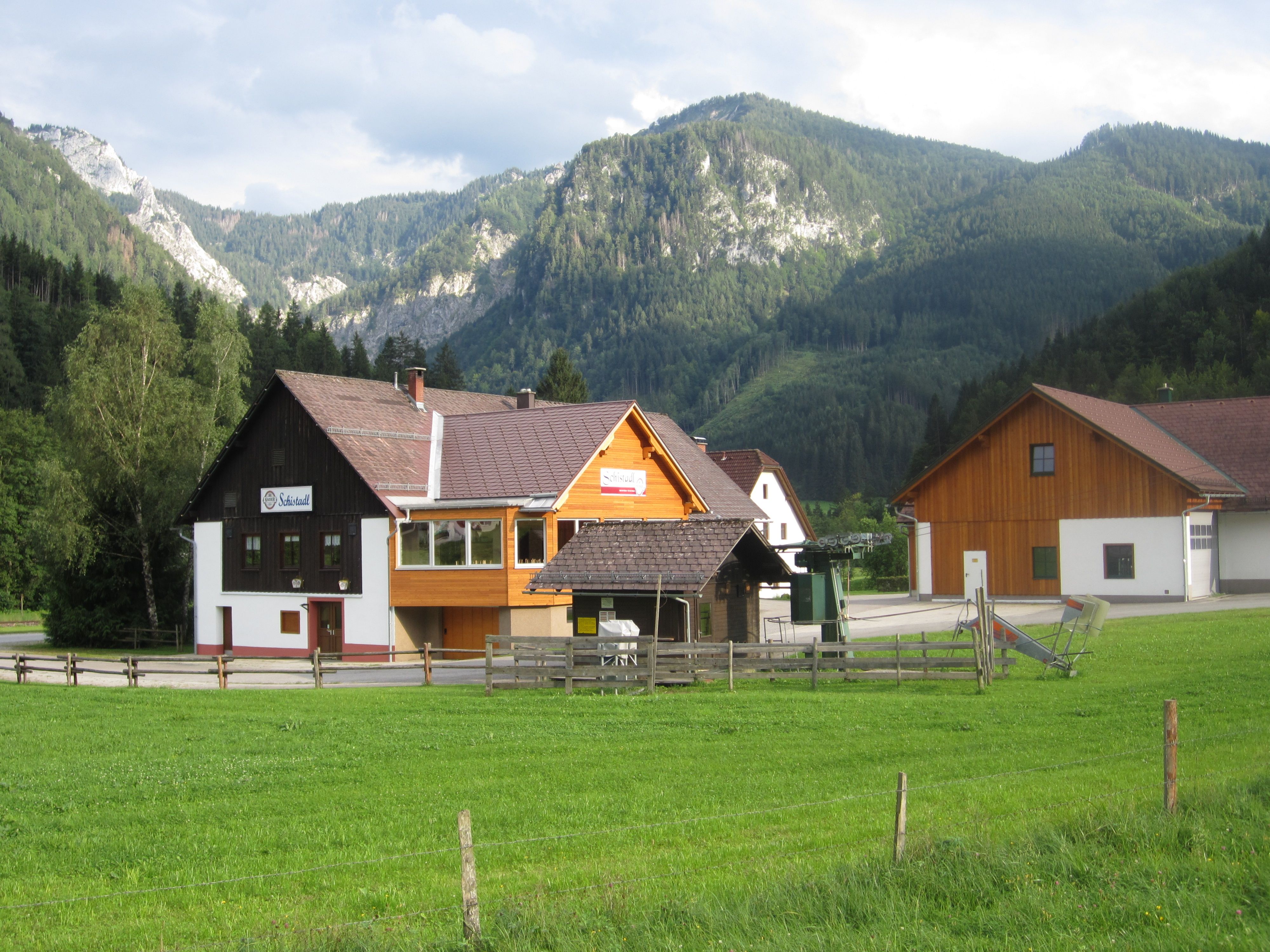 Ein Gebäude mit der Aufschrift 'Schistadl' vor einer Berglandschaft.