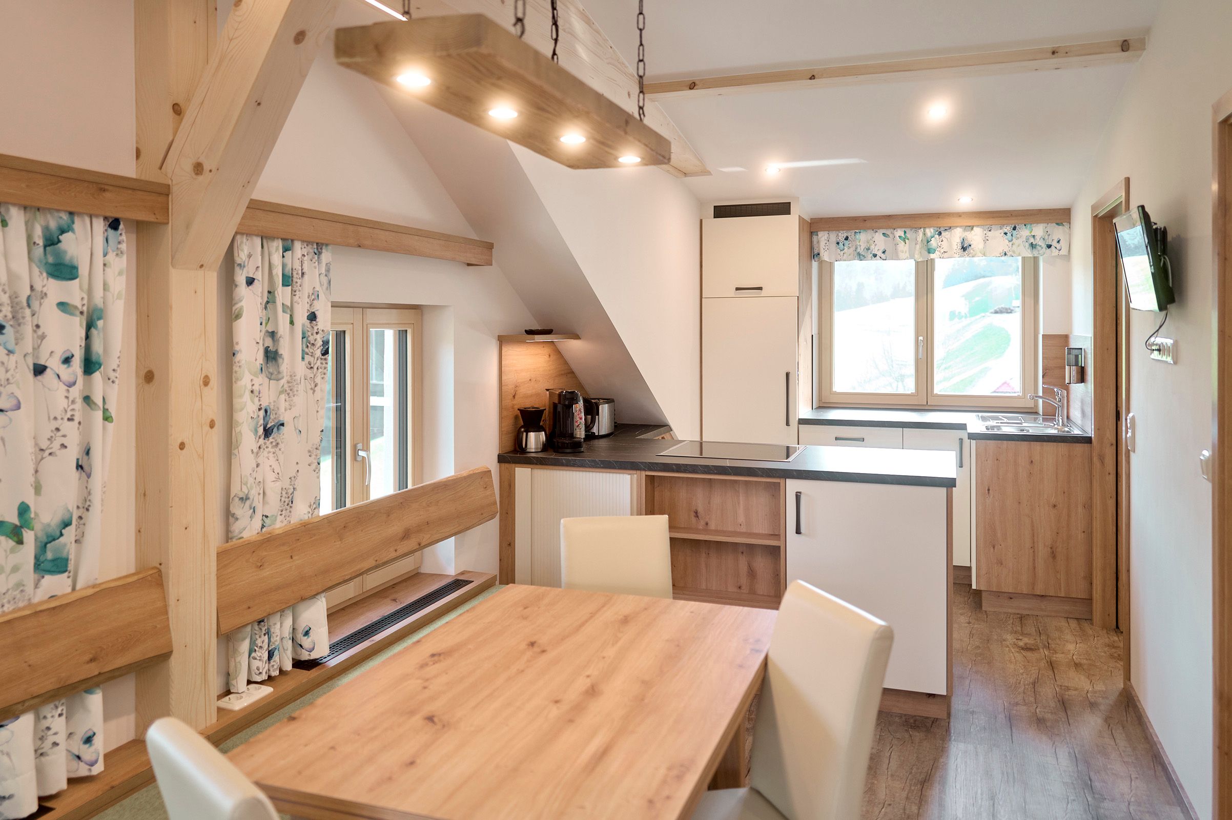 Moderne Wohnküche mit Holzmöbeln und großen Fenstern.