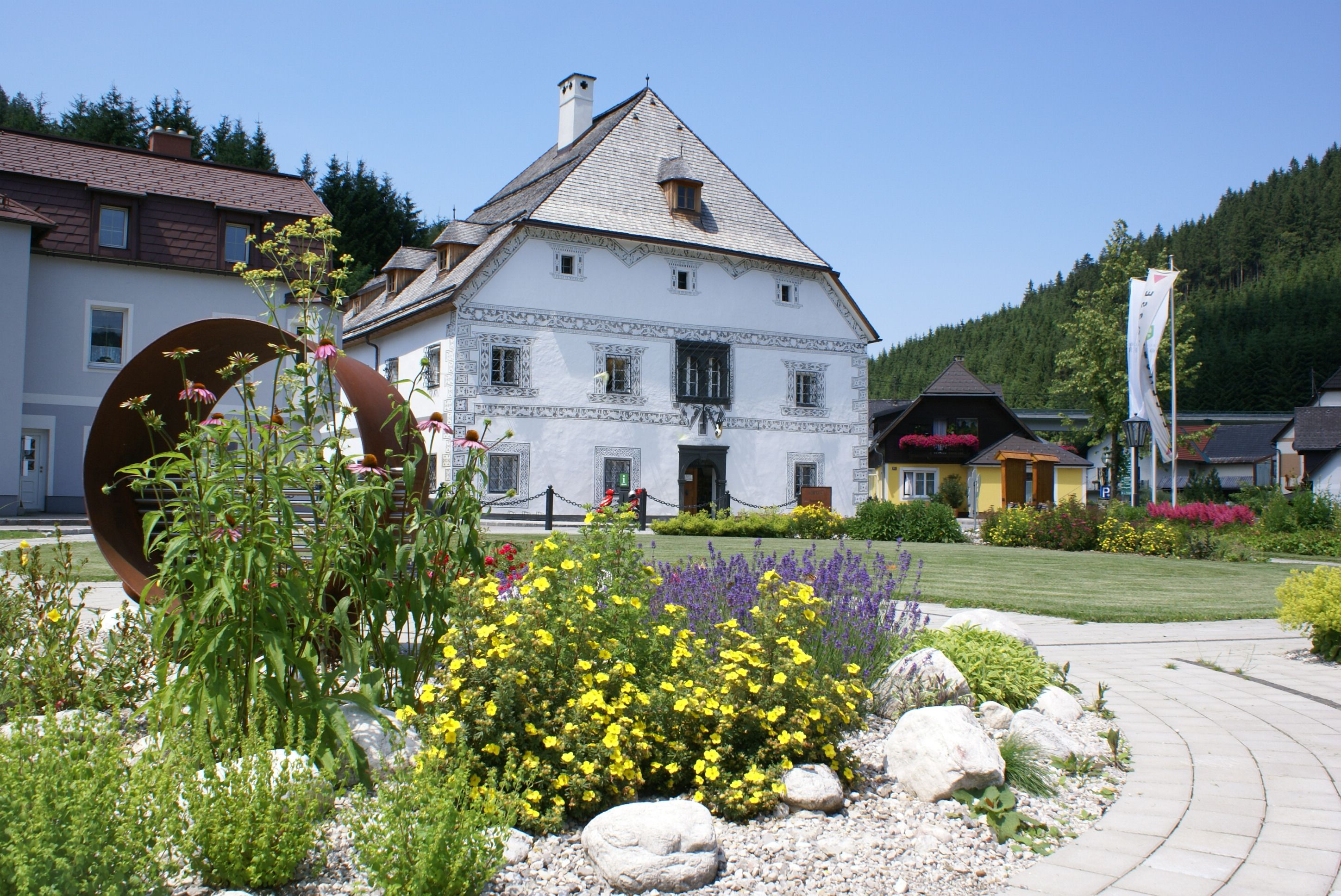 Historisches Gebäude mit Blumenbeet im Vordergrund.