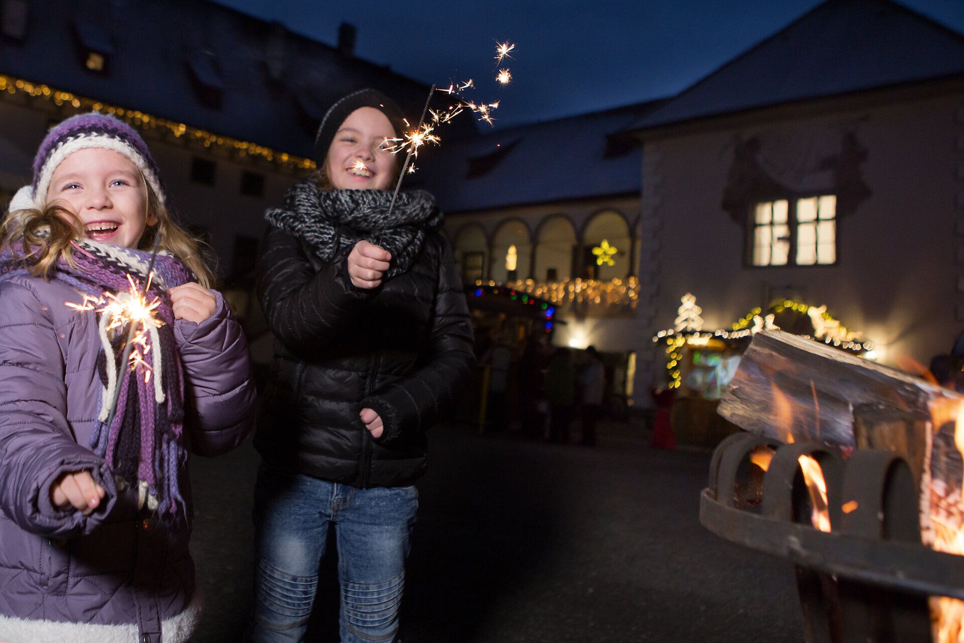 In der festlichen Atmosphäre des Adventmarktes erstrahlen die Kinderaugen vor Freude, während sie mit funkelnden Wunderkerzen spielen. Der Duft von gebrannten Mandeln und Glühwein liegt in der Luft und lädt zum Verweilen ein. Die stimmungsvolle Beleuchtung der historischen Kulisse schafft eine unvergessliche Weihnachtszeit.