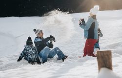 Eine fröhliche Familie genießt den Winter in den Ybbstaler Alpen, während sie sich in einer lebhaften Schneeballschlacht vergnügt. Die glitzernde Schneedecke und die strahlende Sonne schaffen eine magische Atmosphäre, die zum Lachen und Spielen einlädt.