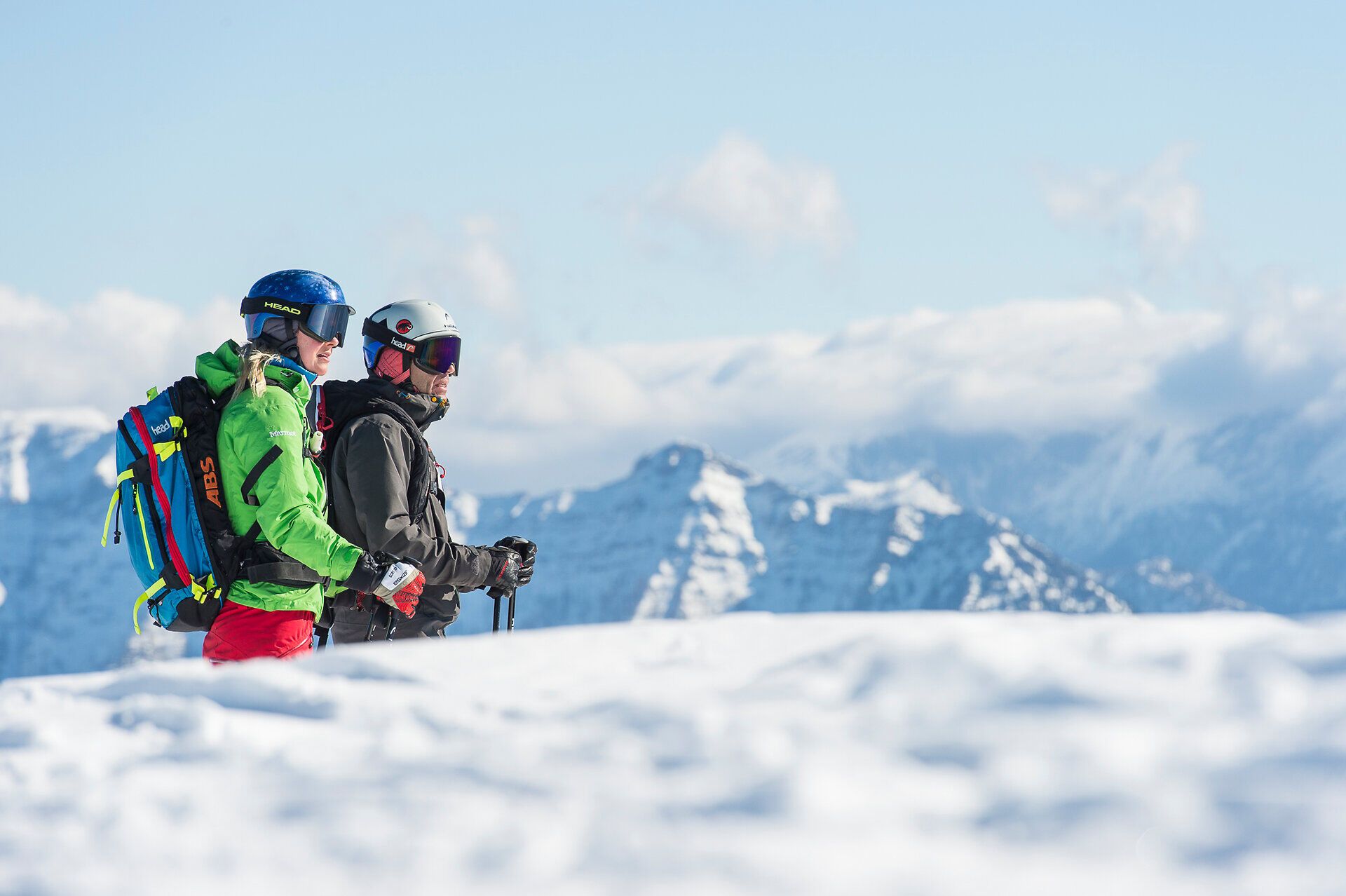 In der glitzernden Winterlandschaft stehen zwei Skitourengeher, umgeben von majestätischen Bergen und unberührtem Schnee. Die frische Bergluft und die strahlende Sonne schaffen eine einladende Atmosphäre für Abenteuerlustige und Naturliebhaber.