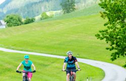 Zwei Radfahrer genießen die frische Bergluft und die atemberaubende Landschaft der Ybbstaler Alpen. Die sanften Hügel und das satte Grün der Wiesen laden zu unvergesslichen Erlebnissen in der Natur ein. Hier wird der Sommer in den Bergen zum wahren Genuss.