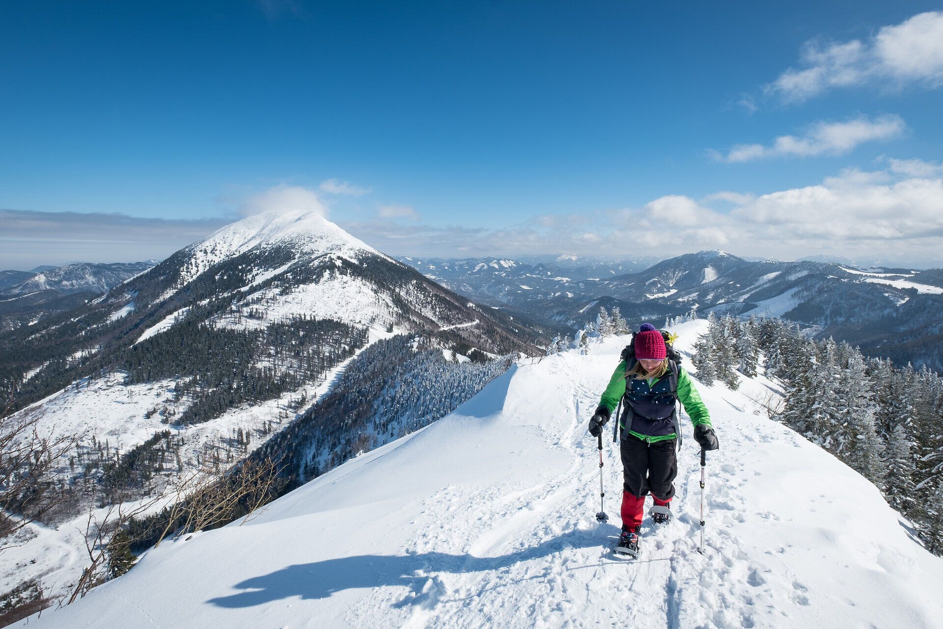 Die glitzernde Schneedecke erstreckt sich über die sanften Hügel des Kleinen Ötschers, während ein Wanderer mit Schneeschuhen den unberührten Winterwald erkundet. Die klare, kalte Luft und die majestätische Berglandschaft schaffen eine Atmosphäre der Ruhe und Erhabenheit, die jeden Naturliebhaber verzaubert.