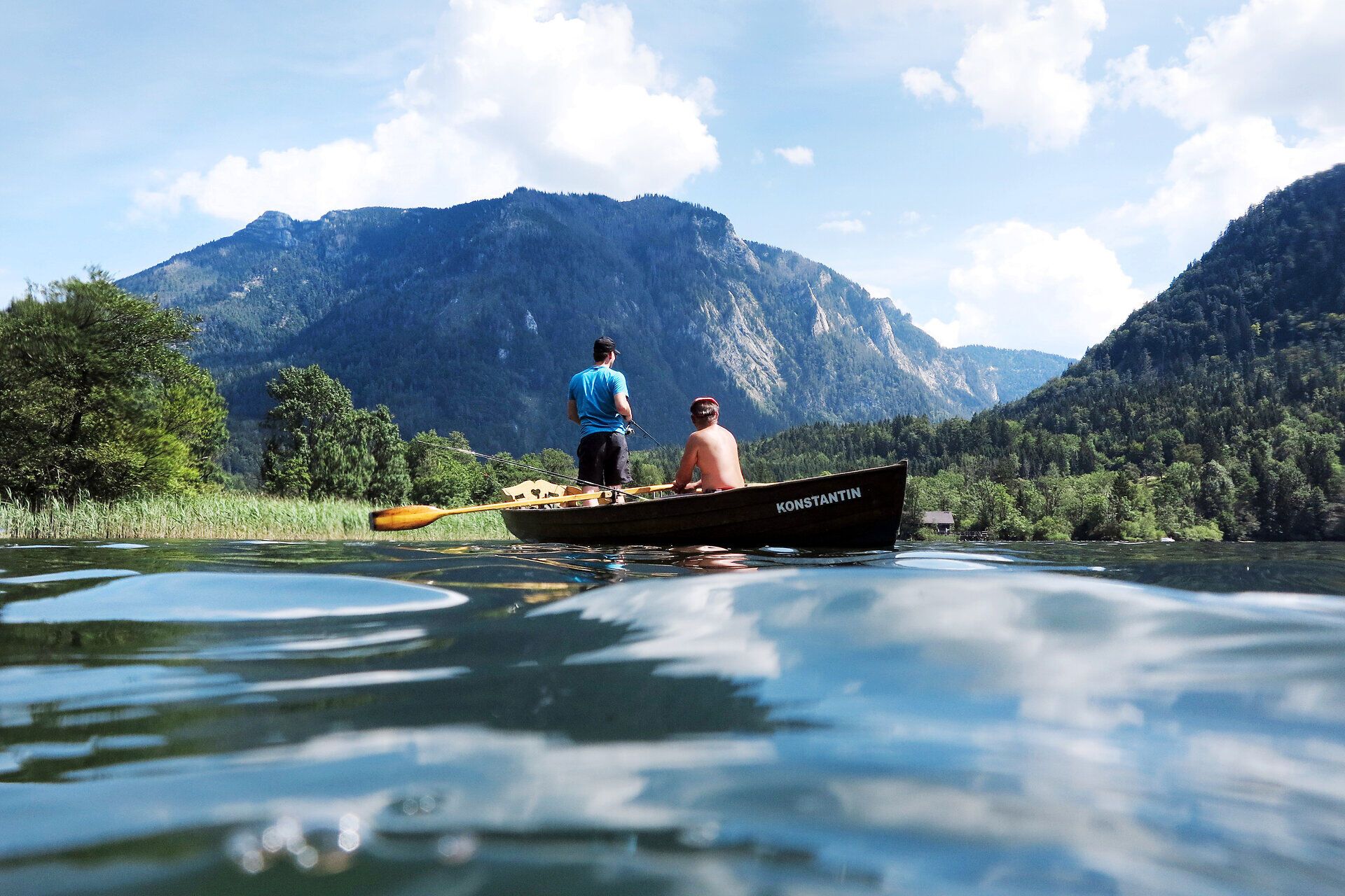 Die sanften Wellen des Lunzer Sees spiegeln die majestätischen Berge der Ybbstaler Alpen wider, während zwei Männer in einem Boot die ruhige Sommerfrische genießen. Umgeben von üppigem Grün und der klaren Bergluft, lädt dieser Ort zum Entspannen und Erkunden ein.