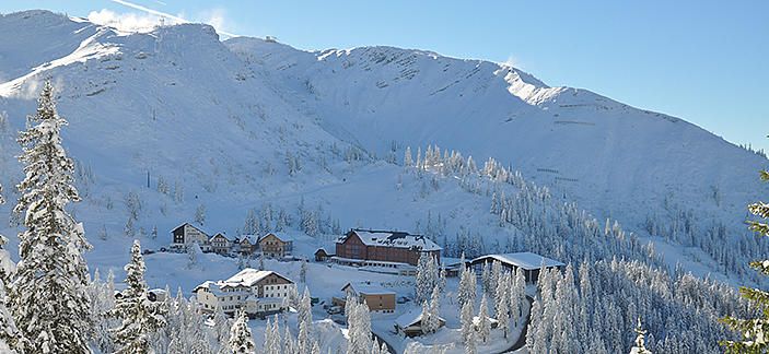 Winterlandschaft mit verschneiten Bergen und Gebäuden am Hochkar.