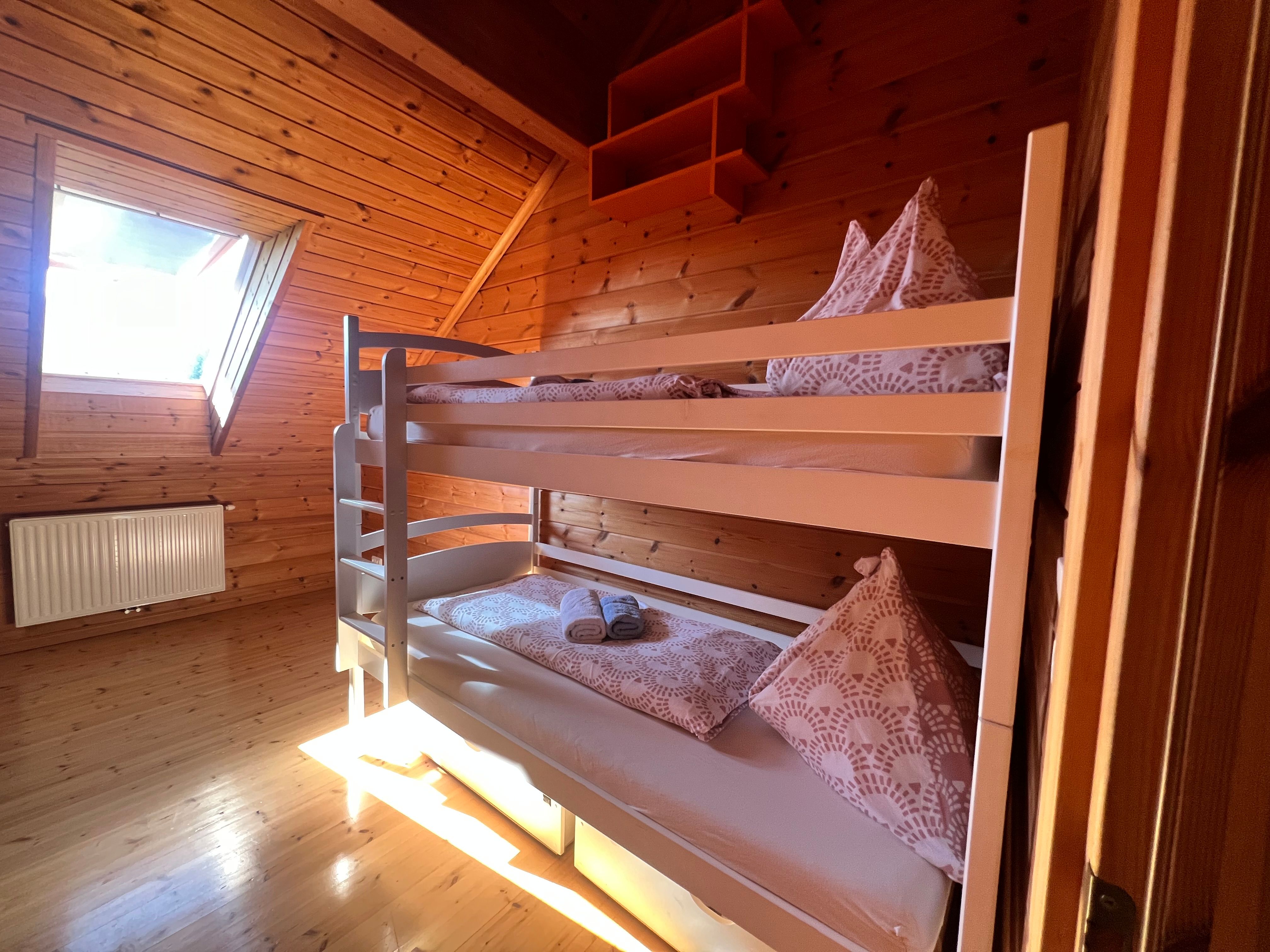 Ein gemütliches Schlafzimmer mit Holzverkleidung und einem Etagenbett unter einem Dachfenster.