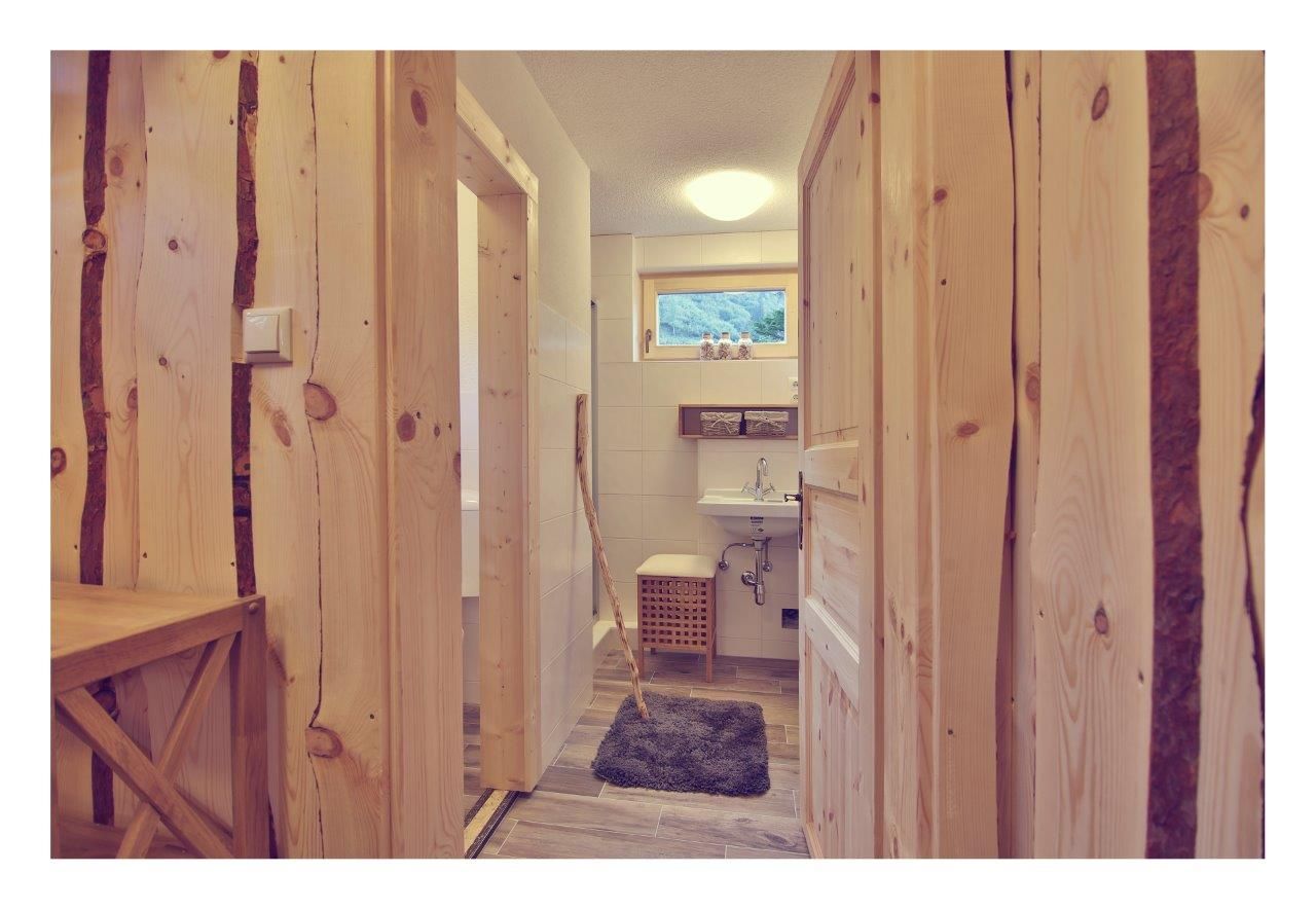 Innenansicht eines Badezimmers in einem Chalet mit Holzwänden und -türen, Waschbecken und kleinem Fenster.