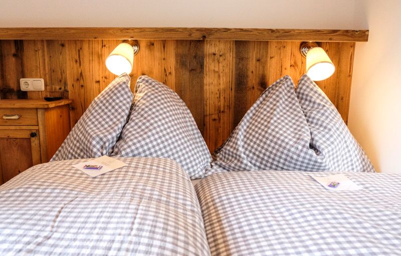 Gemütliches Schlafzimmer mit karierten Bettdecken und Holzvertäfelung.