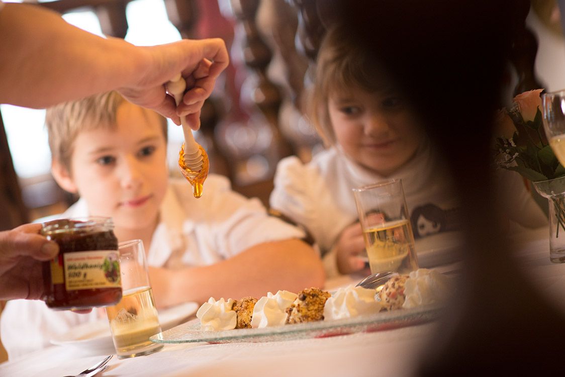Zwei Kinder beobachten, wie Honig auf ein Dessert geträufelt wird.