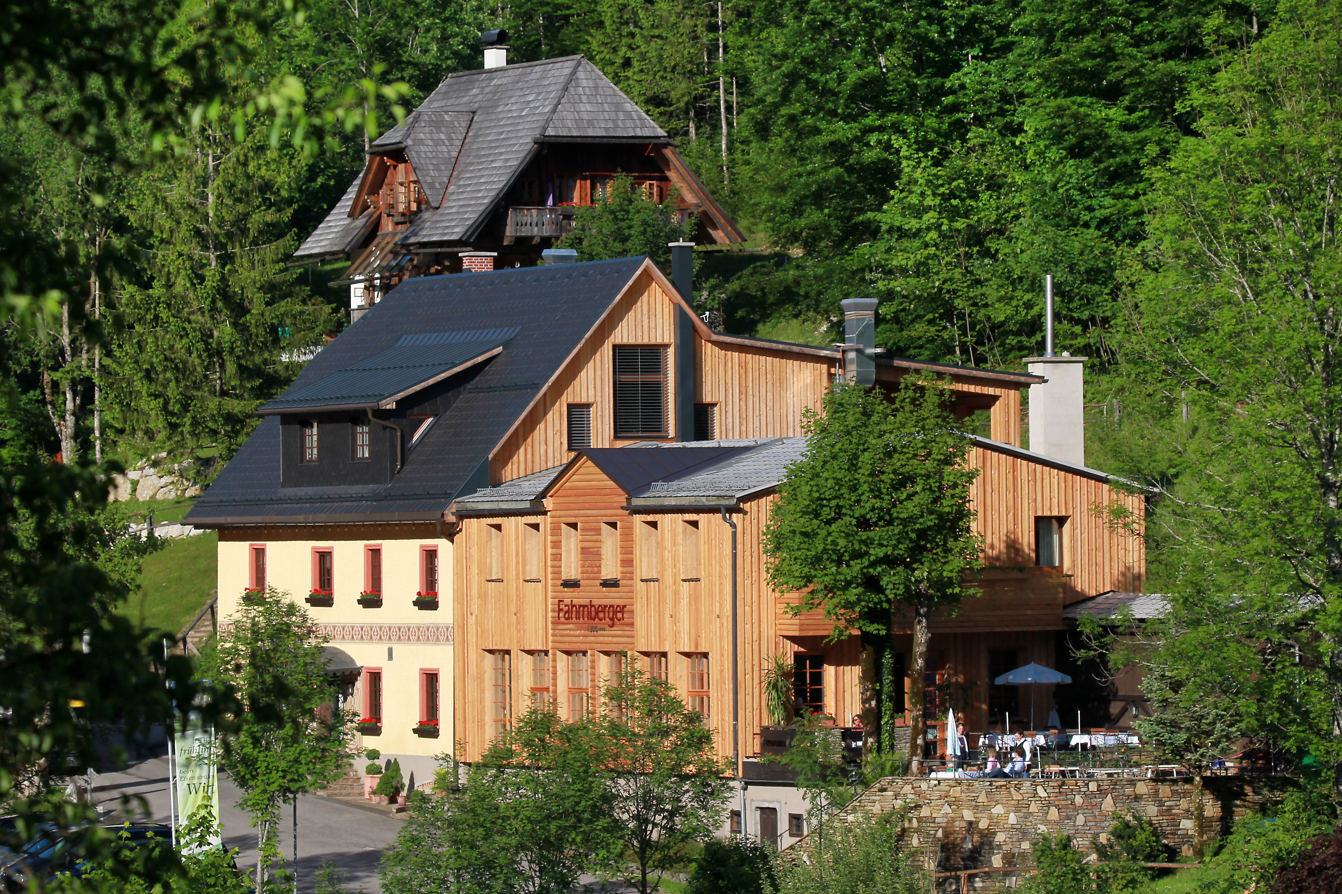 Ein traditionelles Gebäude mit Holzfassade in einer grünen Waldlandschaft.
