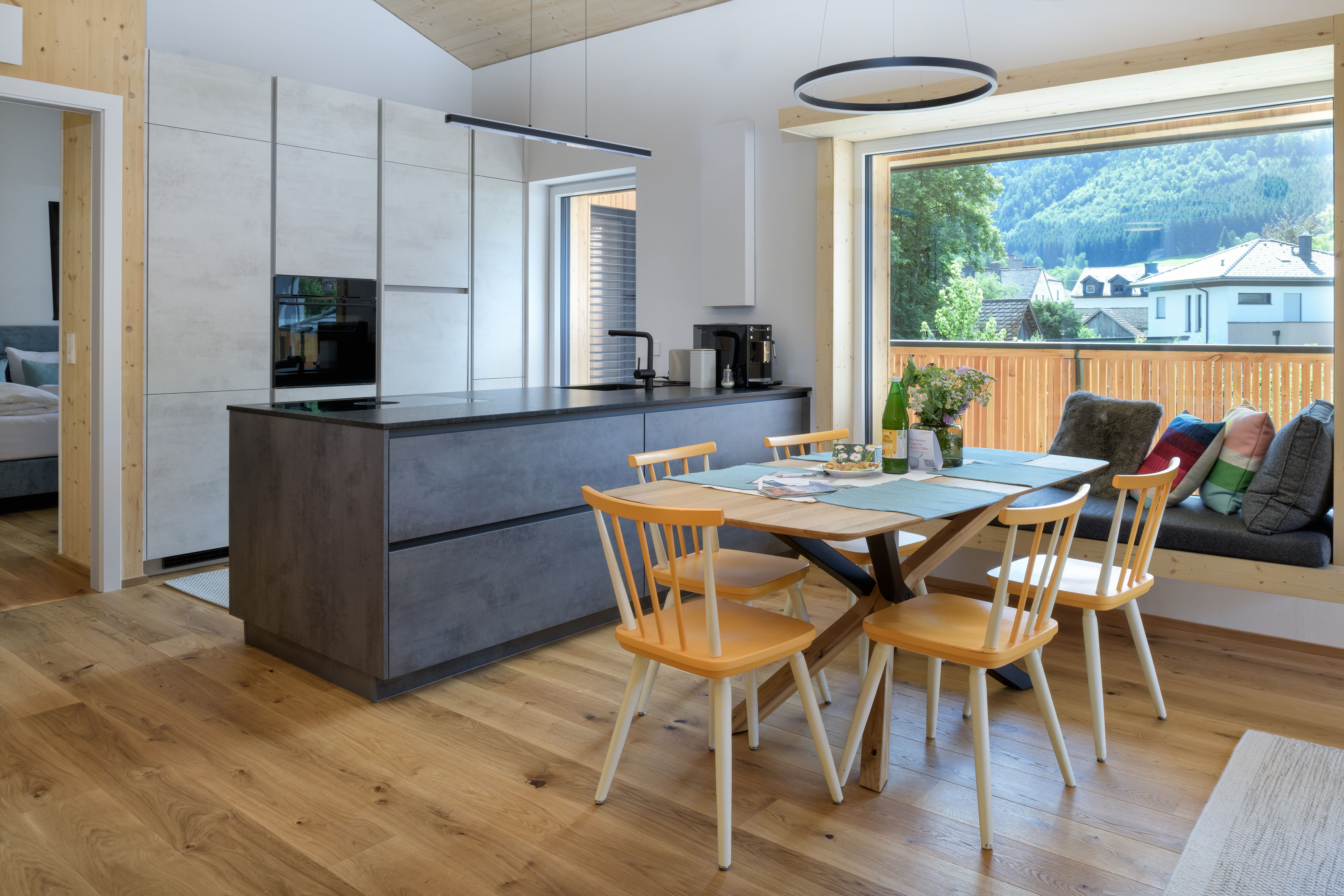 Moderne Küche mit Esstisch und großem Fenster mit Bergblick.