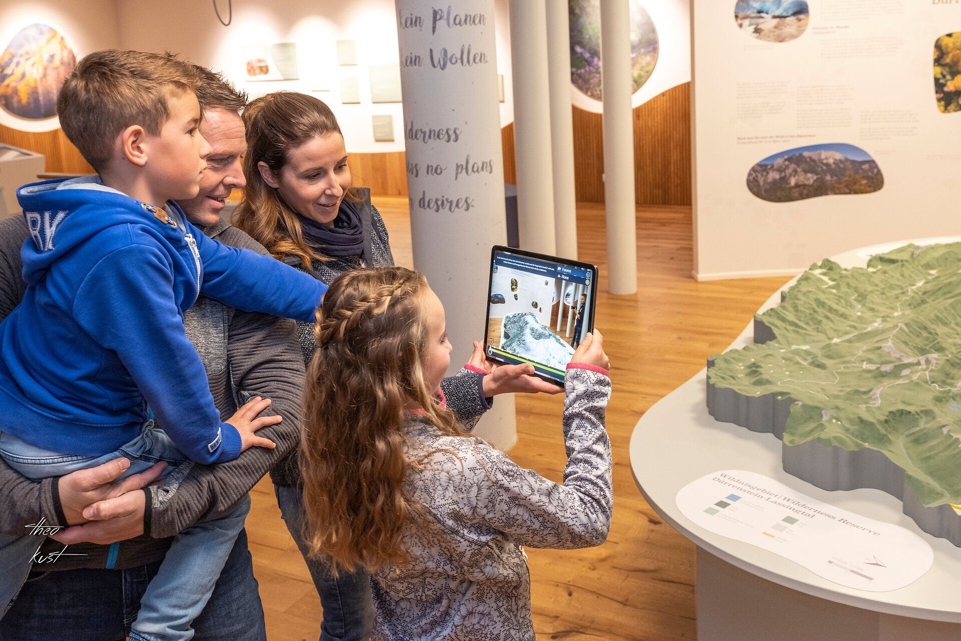 Eine Familie erkundet gemeinsam die faszinierenden Ausstellungen im Haus der Wildnis. Die Kinder sind begeistert von den interaktiven Elementen, während die Eltern die beeindruckenden Informationen über die Natur und die Tierwelt genießen. Ein perfekter Ort für einen lehrreichen und unterhaltsamen Ausflug an einem regnerischen Tag.