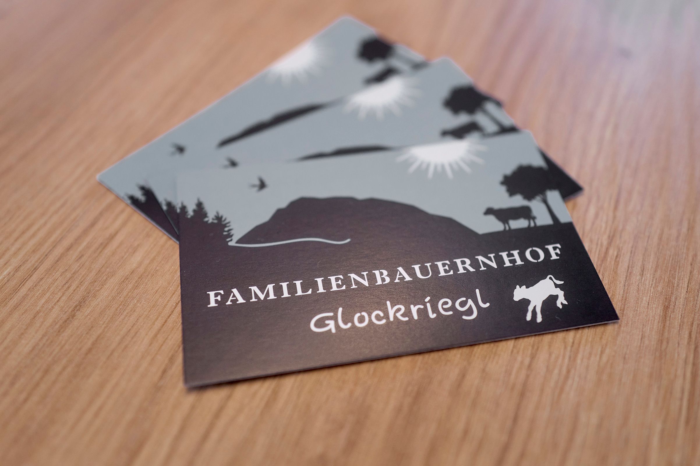 Postkarten mit dem Logo des Familienbauernhofs Glockriegl auf einem Holztisch.