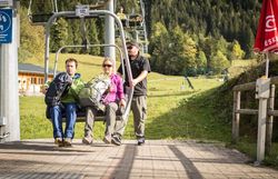 Die frische Bergluft umhüllt die Wanderer, während sie auf dem Sessellift sanft in die Höhe gleiten. Umgeben von üppigen Wäldern und majestätischen Gipfeln, spüren sie die Vorfreude auf das Abenteuer, das sie erwartet. Hier, wo die Natur in voller Pracht erstrahlt, wird jeder Moment zum unvergesslichen Erlebnis.