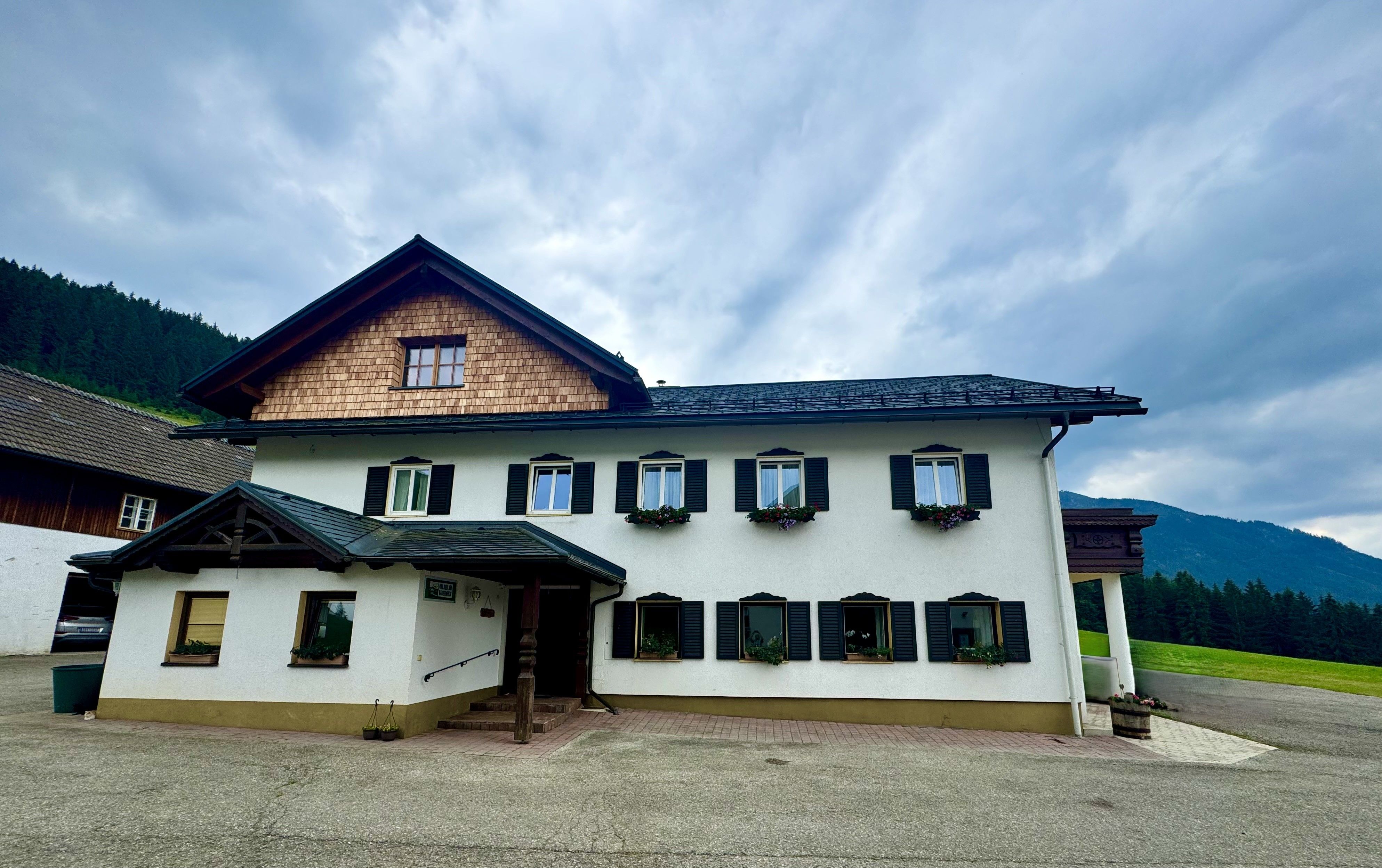 Ein traditionelles zweistöckiges Bauernhaus mit weißen Wänden und schwarzen Fensterläden.
