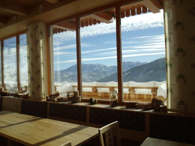 Blick aus einem Fenster auf verschneite Berge und blauen Himmel.