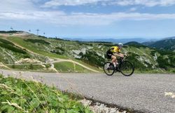 Ein Rennradfahrer bei der Auffahrt auf der Hochkar-Bergstraße, im Hintergrund ist die Hochkarbahn zu sehen.