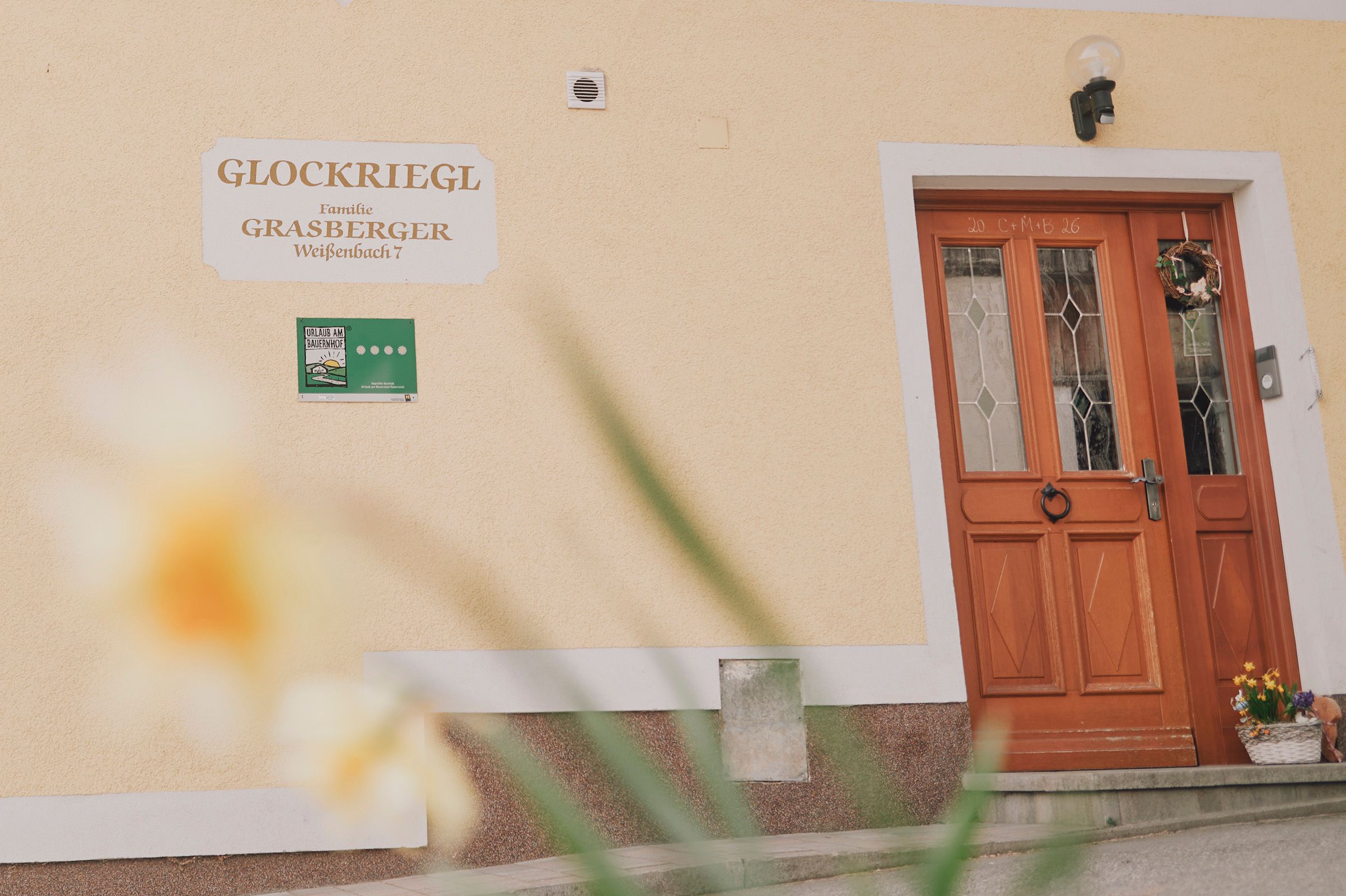 Eingang eines Hauses mit Holztür und Schild "Glockriegl" an der Wand.