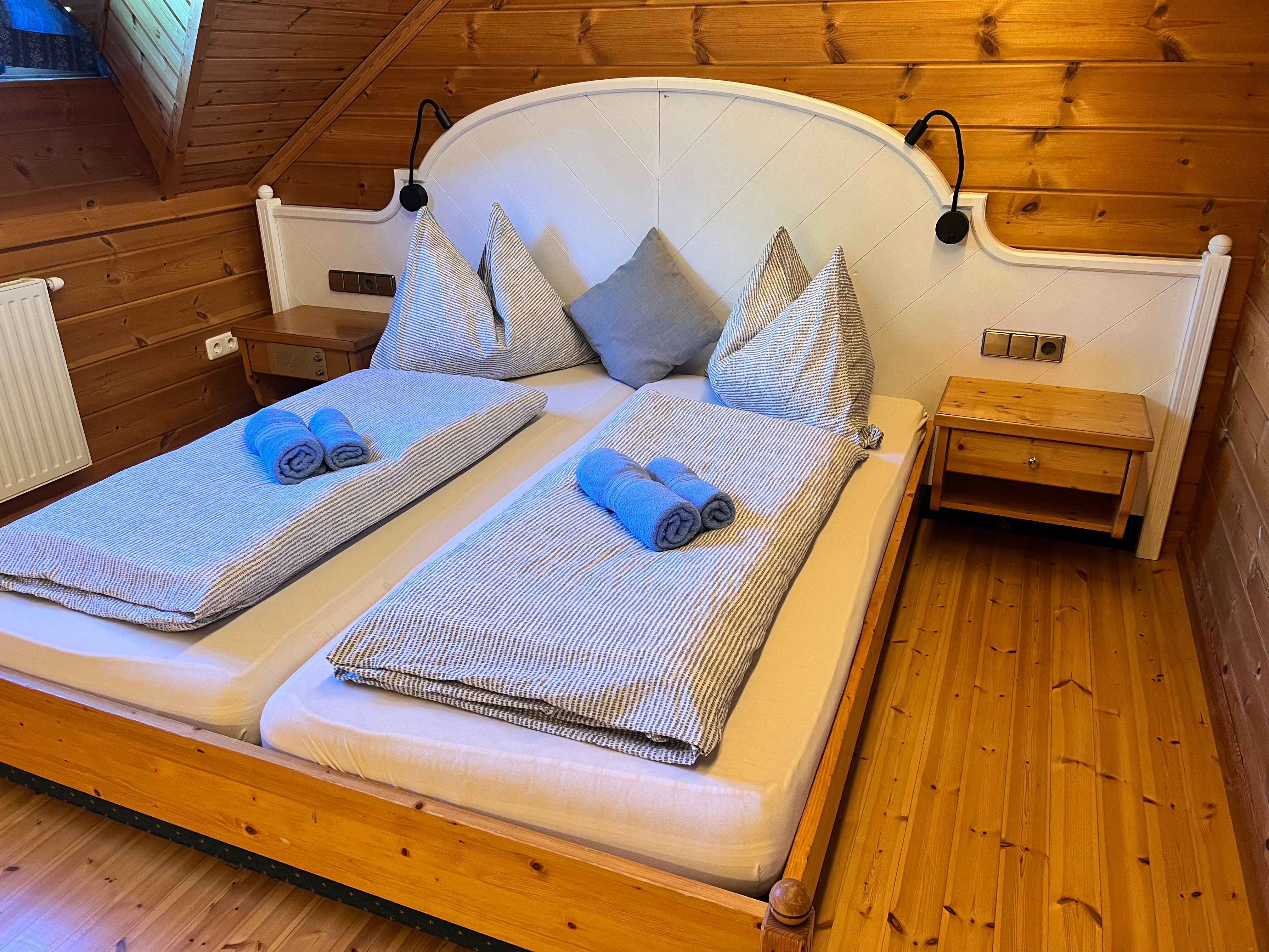 Gemütliches Schlafzimmer mit Holzwänden und einem Doppelbett, das mit blauen Handtüchern und gestreifter Bettwäsche dekoriert ist.