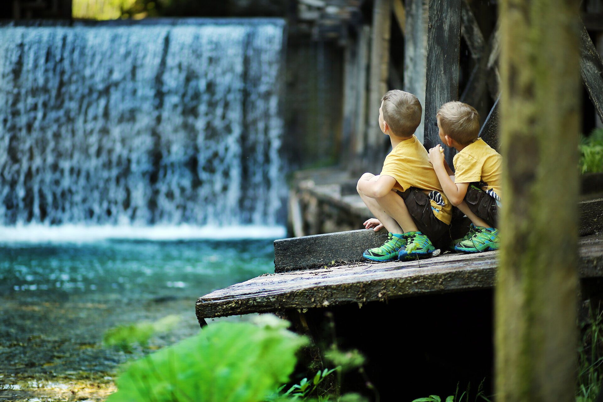Zwei Kinder sitzen am Ufer eines glitzernden Baches und beobachten fasziniert das plätschernde Wasser, das über die Steine fließt. Umgeben von üppigem Grün und dem sanften Rauschen der Natur, erleben sie einen unvergesslichen Moment der Kindheit in der idyllischen Landschaft. Hier im Mendlingtal wird der Familienurlaub zum Abenteuer voller Entdeckungen.