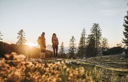 Die sanften Hügel der Ybbstaler Alpen laden zu einem unvergesslichen Abenteuer ein. Zwei Wanderer genießen den atemberaubenden Sonnenuntergang, während die goldenen Strahlen durch die Bäume scheinen und die Landschaft in ein warmes Licht tauchen. Hier, inmitten der Natur, wird jeder Schritt zu einem Erlebnis der Ruhe und Schönheit.